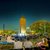Abendveranstaltung im Freien mit vielen Zuschauern, die auf Liegestühlen und Decken sitzen und einem beleuchteten Turm im Hintergrund, der von Bäumen umgeben ist.