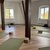 Yogaräume mit mehreren grünen Yogamatten auf hellem Holzfußboden, zwei Fenster mit Tageslicht, einige Matten mit Meditationskissen oder Decken belegt, ruhige Atmosphäre für Entspannung und Yogaübungen.